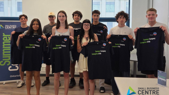Group of teenagers participating in the 2025 Summer Company program, holding up Summer Company t-shirts