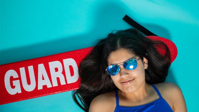 Young woman with sunglasses on and a lifeguard board