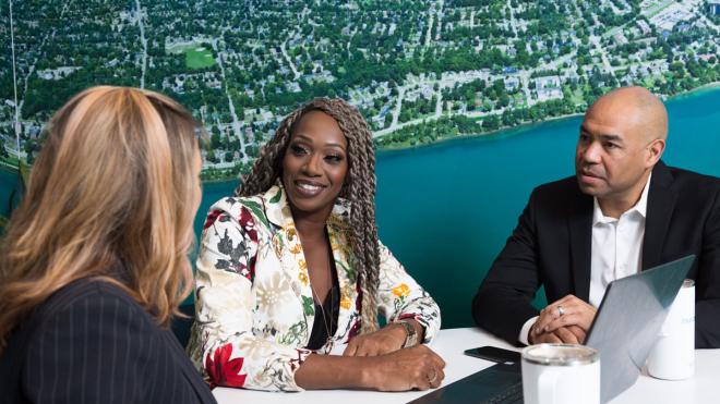 Three people sitting around a laptop during a meeting