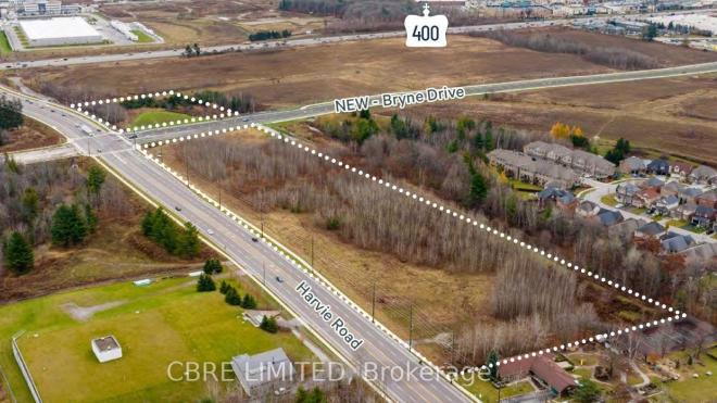 Aerial view of land parcel at an intersection, with nearby residential area and fields.