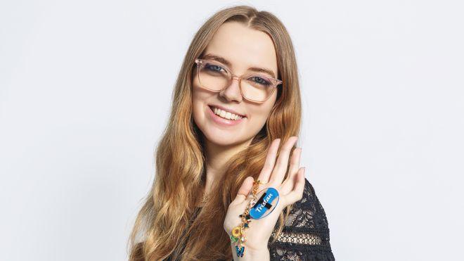 Smiling woman with long hair, wearing glasses, holding keychain.