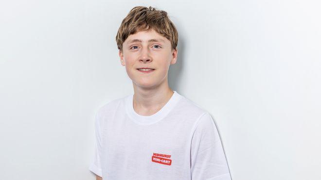 Young person in a white t-shirt against a white background, smiling subtly.
