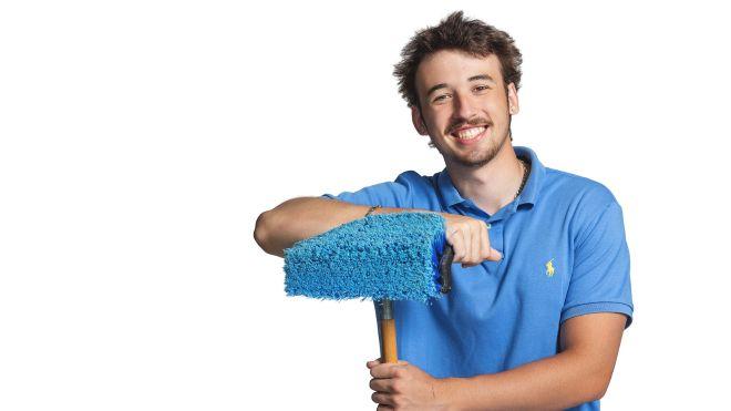 Man in blue shirt smiling, holding a mop against a white background.