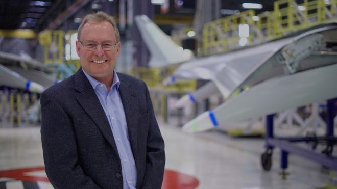 Man smiling in an aircraft manufacturing facility.