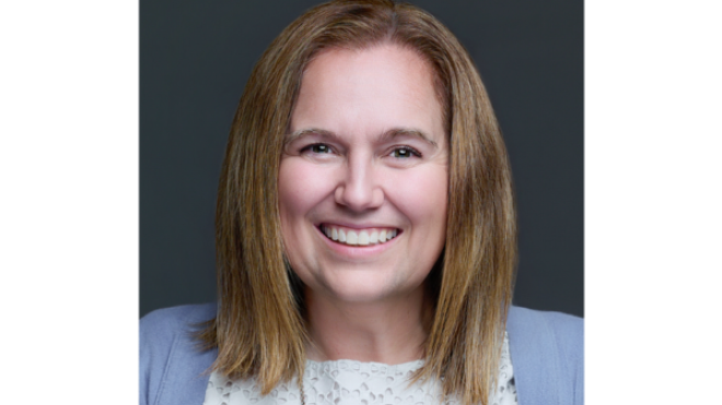 Smiling person with shoulder-length hair against a dark background.