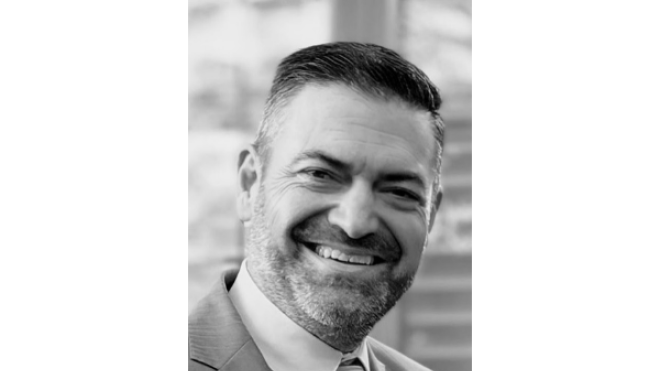 Smiling man in a suit, grayscale portrait.