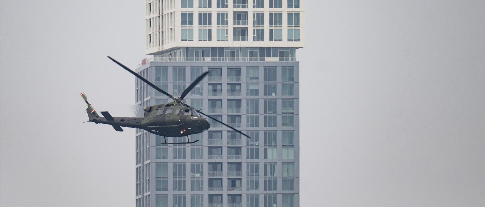 Helicopter flying past tall building.