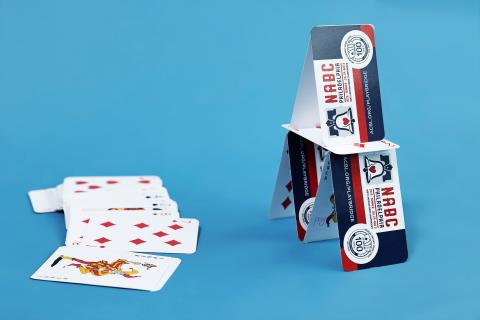 Playing cards stacked as a house against a blue background.