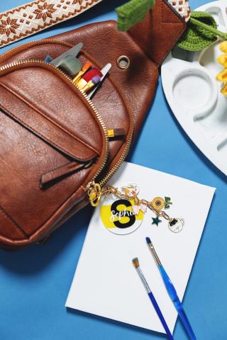 Backpack, art supplies, canvas, and paintbrushes on a blue surface.