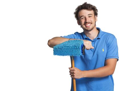 Man in blue shirt smiling, holding a blue mop.