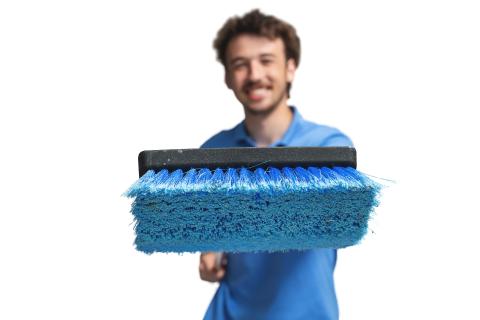 Smiling man holding a large blue brush toward the camera.